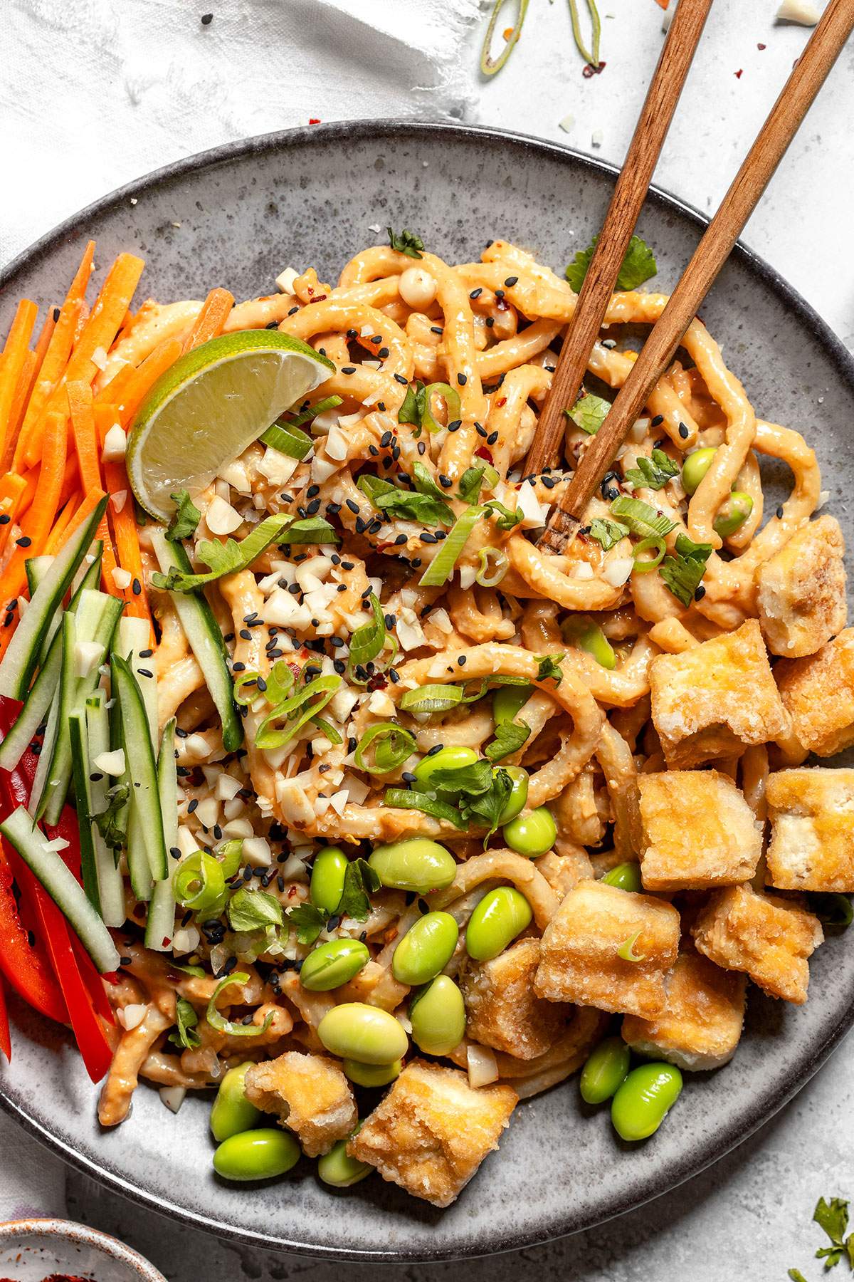 close up of vegan peanut noodles with a pair of chopsticks