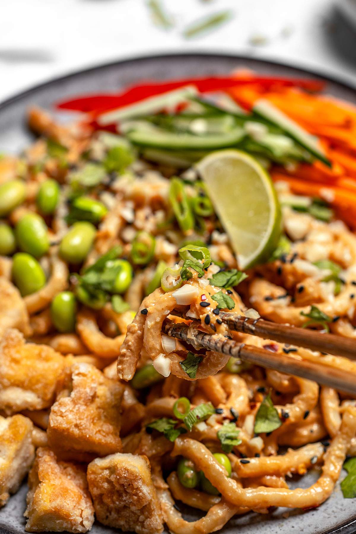 close up of vegan peanut noodles picked up with a pair of chopsticks