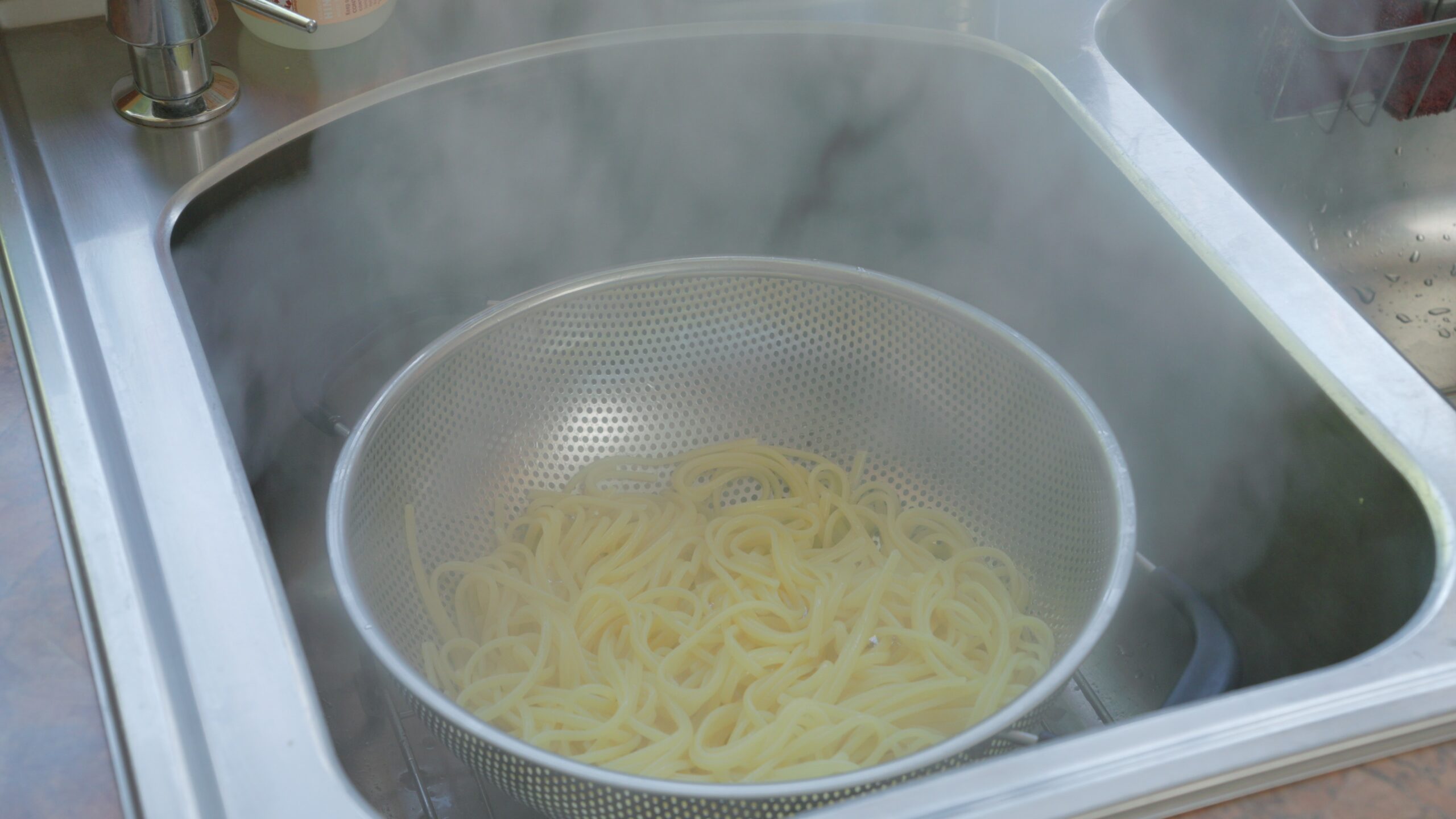 noodles draining in a colander in the sink