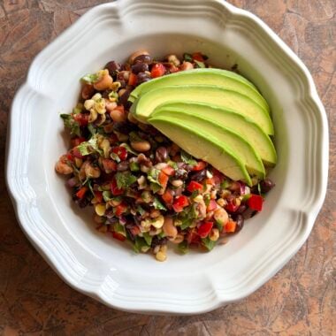 overhead shot of cowboy caviar in a bowl topped with avocado