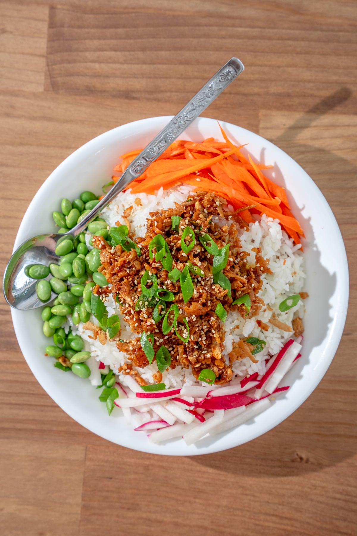 overhead shot of rice, tofu bulgogi, carrot, edamame, radish, and sliced scallions