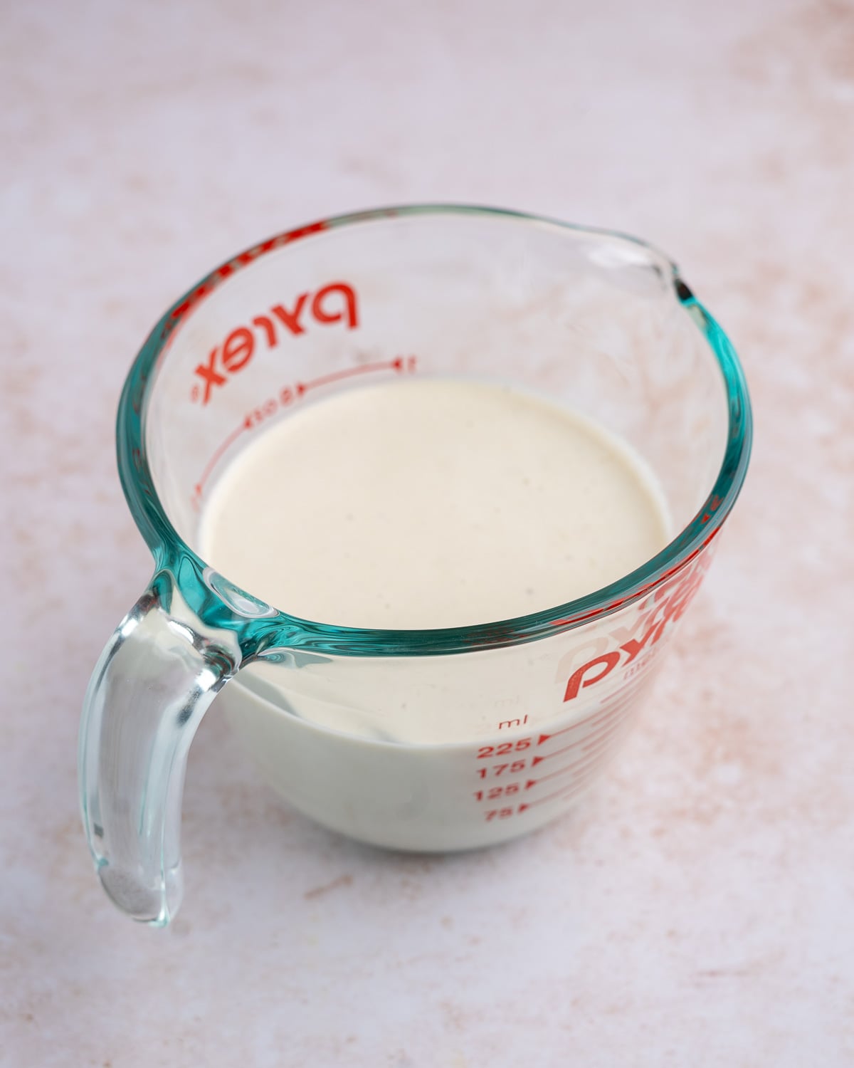 A Pyrex measuring cup full of smooth cashew cream.